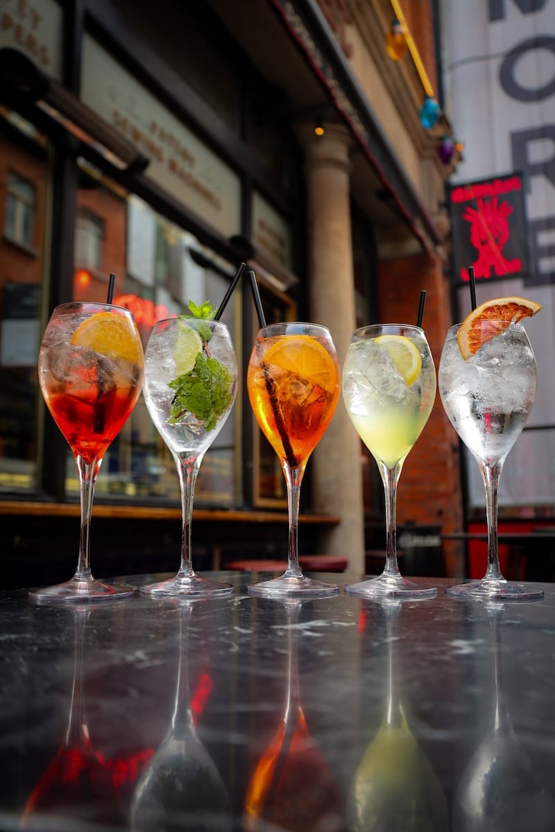 Five colourful spritz cocktails on outdoor table
